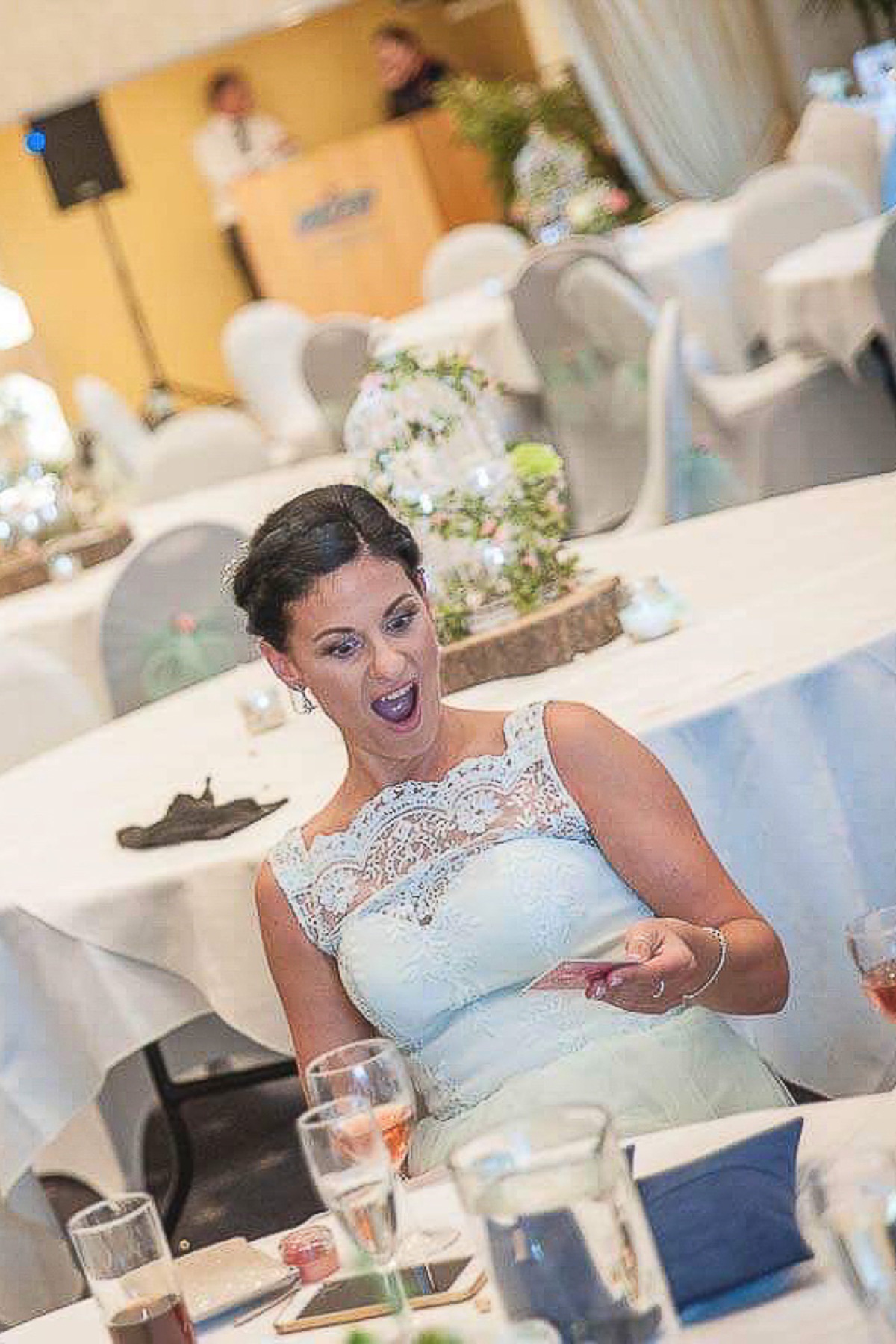 A bride reacting with delight during table magic at her wedding reception