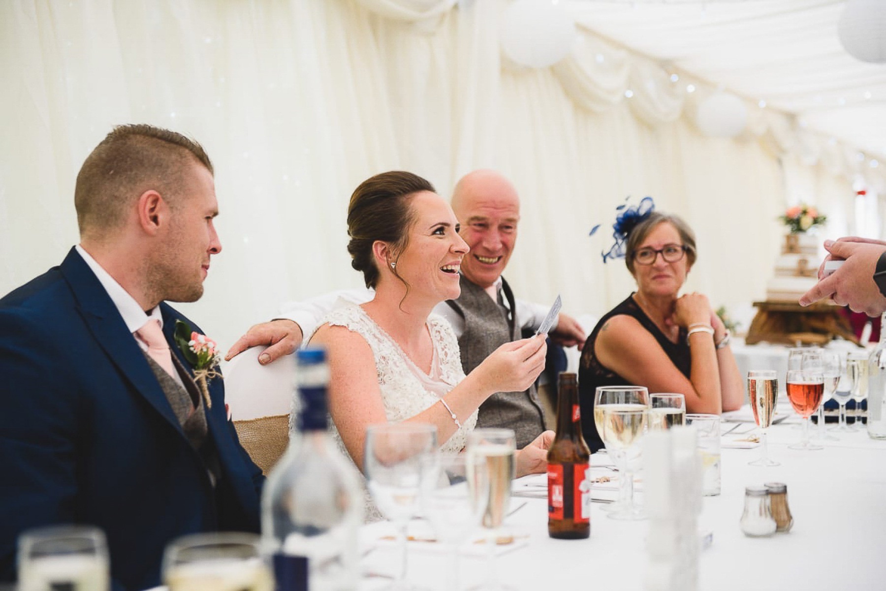 A bride and her wedding guests smiling during close-up magic at the top table